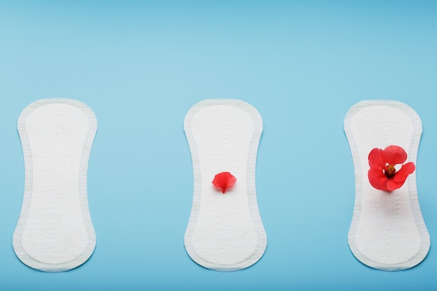 Three Sanitary pads on blue. The concept of critical days, menstrual cycles in several stages.