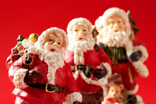 Three Santa Claus figurines over red 