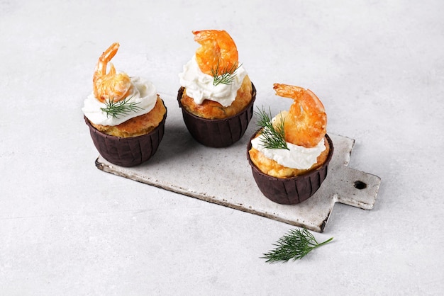 Three savory muffins with shrimps and cheese on gray background copy space