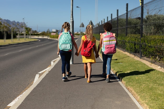 Foto tre studentesse che camminano lungo una strada per la scuola elementare