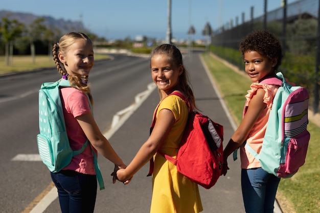 Photo three schoolgirls walking along a road to elementary school