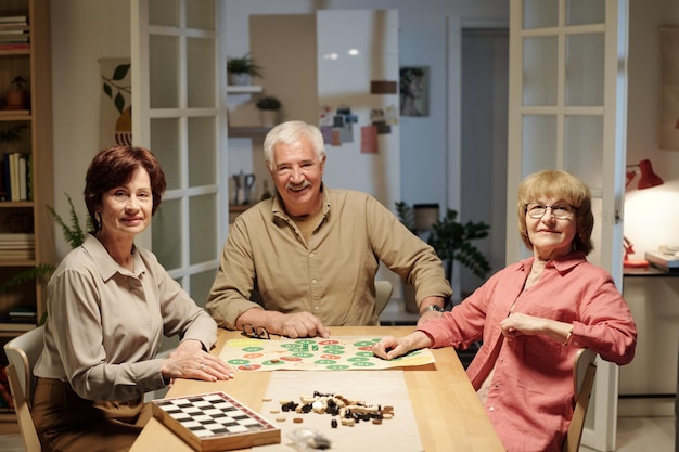 Three senior happy people in shirts looking at you during leisure game