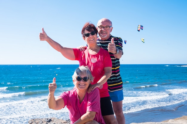 写真 崖の上で友情の3人の高齢者。屋外での笑いと幸せ。青い空と波のある海。ウィンドサーフィンやカイトサーフィン愛好家のためのパラダイス
