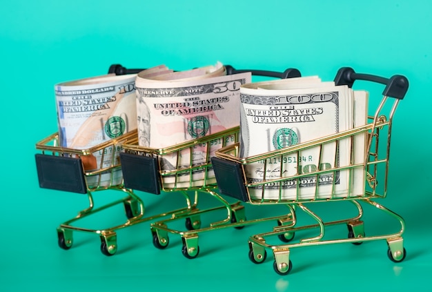 Three shopping baskets with dollars in them on a turquoise background. Financial and banks concept.