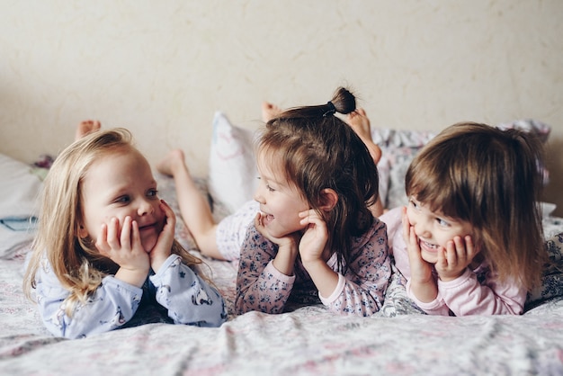 Three sisters lie side by side on the bed