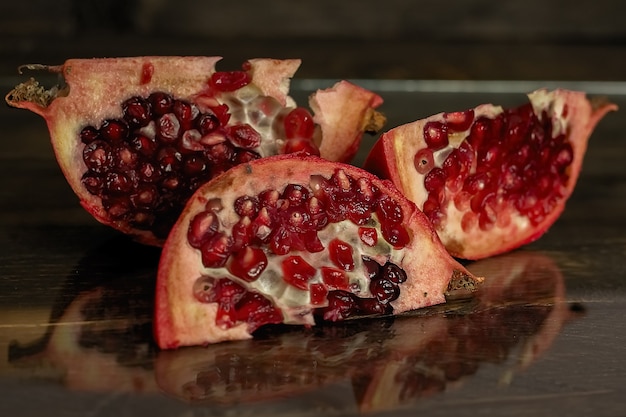 Three slices of the cut pomegranate lie on a wooden board.