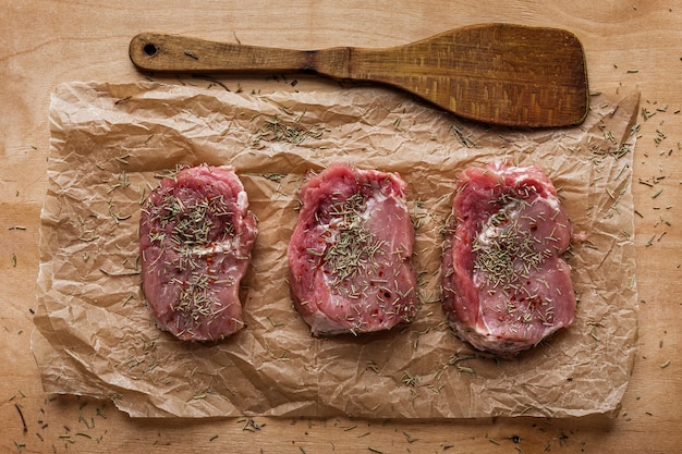 Three slices of raw meat and wooden spatula