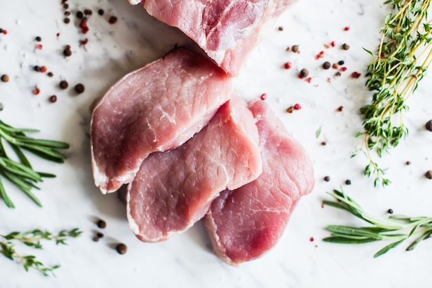 Three slices of raw pork tenderloin with spices