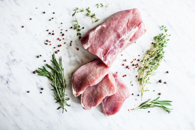 Three slices of raw pork tenderloin with spices