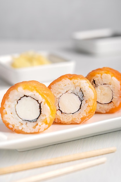 Foto tre fette di sushi roll fatti con salmone crudo formaggio crema alghe e riso sul piatto sulla tavola