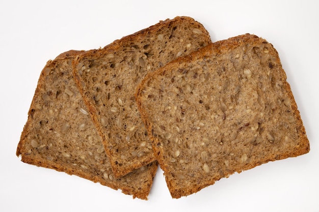 Three slices of wholegrain bread with seeds of sunflower, flax, and sesame. Healthy vegetarian food. Isolated flatlay.