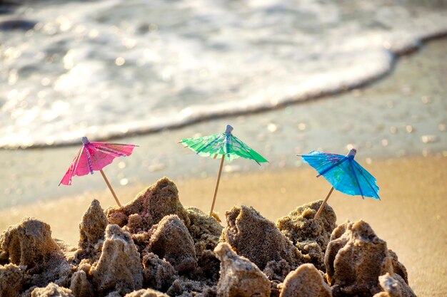 Three small beach umbrellas made of paper for cocktail stand in sand