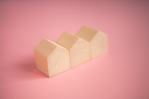 Three small cute wooden houses on pink background