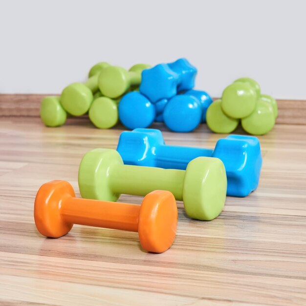 Three small rubberized dumbbells of different weights lie on the floor