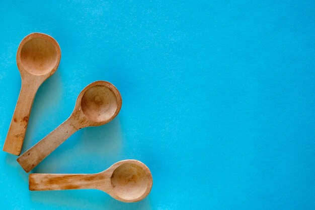 Three small wooden spoons next to each other on a blue surface