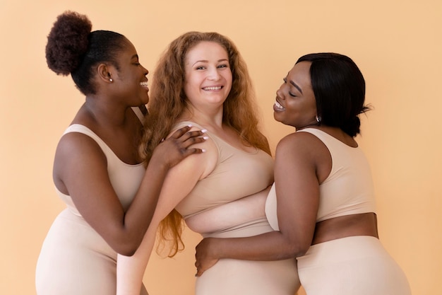 Photo three smiley women in nude body shapers posing together