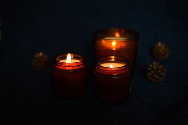 three soy candles in dark candlesticks on a dark background. mysticism, mystery, halloween spirit