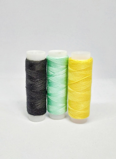 Three spools of thread with a yellow, green, and black color.