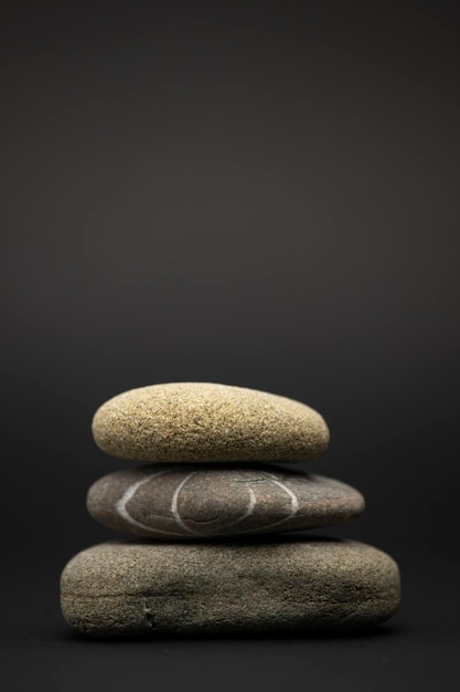 three stones are stacked isolated on a black background zen stone concept