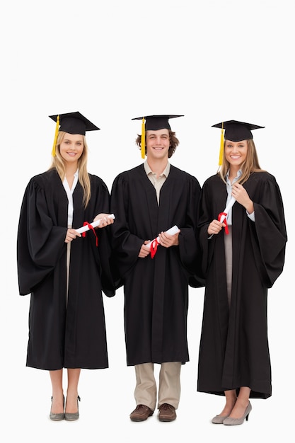 Three students in graduate robe holding a diploma