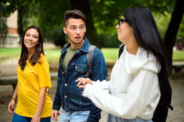 Three students talking to each other outdoor in a college courtyard