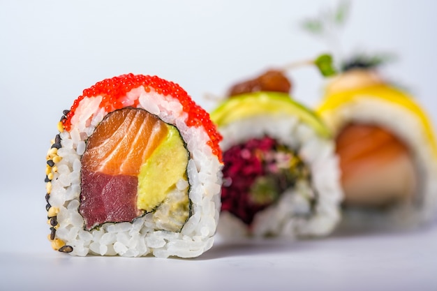 Three sushi rolls with salmon, avocado, tuna and cucumber isolated on white