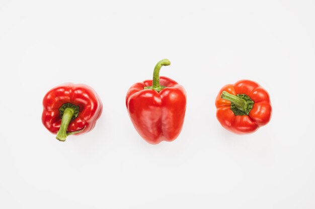 Three sweet red bell peppers on white background Top view copy space