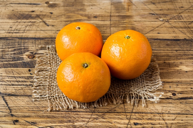 Three tangerines on a napkin on a wooden rustic table.