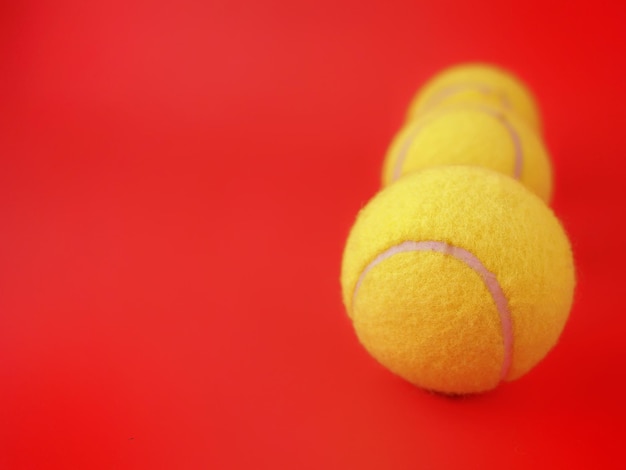 Three tennis balls are arranged on a red background.