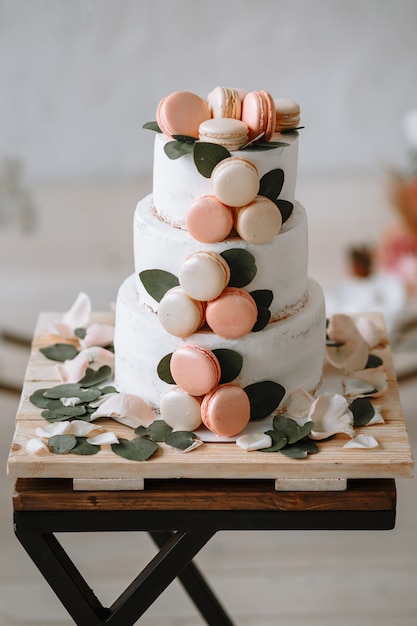 Three-tiered wedding cake on a stand on the background of the arch