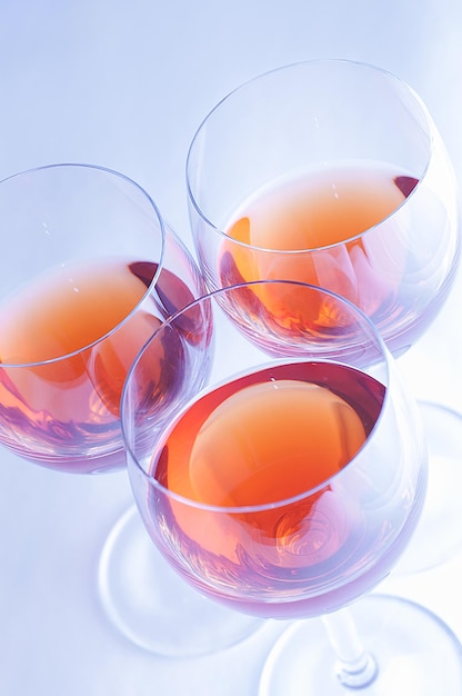 Three transparent wineglasses with rose wine Blue background