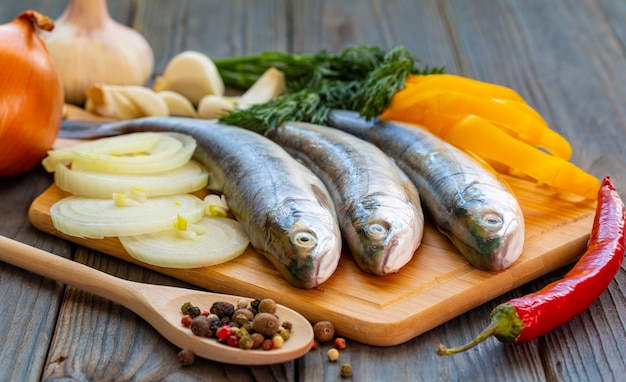 The three trout fish with peppers, onion and garlic on wooden board