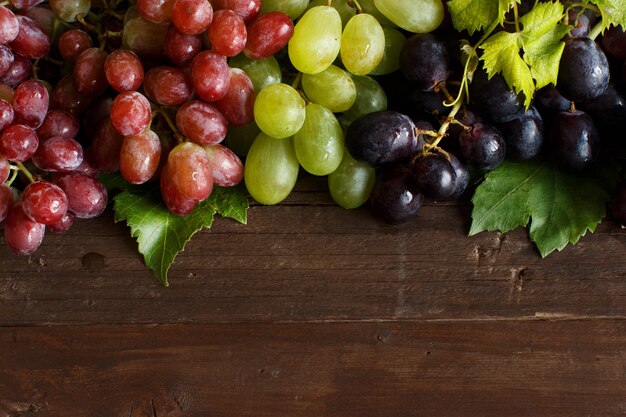 Three types of grapes on a wooden surface