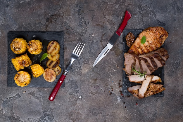 three types of grilled steak (chicken, pork, beef) on slate plate with herbs