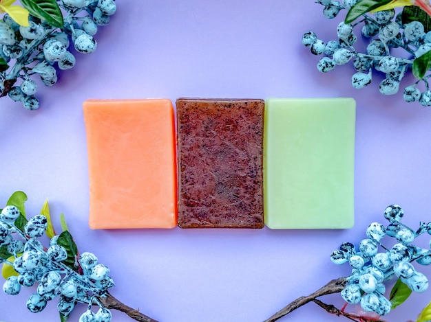 Three types of natural handmade soap in purple decoration with berries.