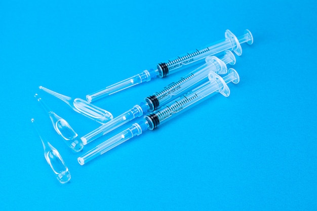 Three vaccines for covid in ampoules and syringes lying on blue