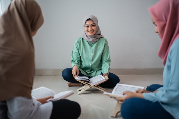 Three veiled women sitting on the floor while studying the Qoran