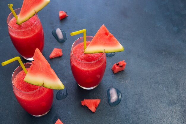 Three watermelon smoothies on a blue table