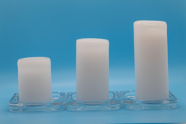 Three White Candles on Blue Background in Ascending Order