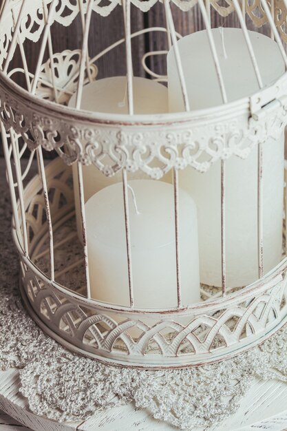 Foto tre candele bianche di natale all'interno della gabbia per uccelli. arredamento shabby chic