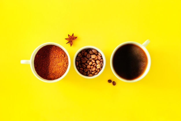 Photo three white cups with ground coffee beans black brewed coffee in the rays on a yellow