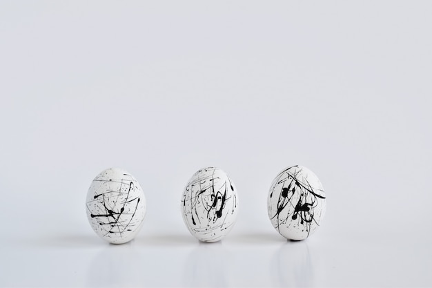 Три белых яйца с крапинками на белом. Минимальная концепция Пасхи. Пасхальная открытка с пространством для текста. Геометрия.