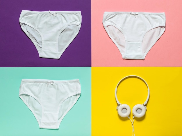 Three white panties and headphones on a colored background Underwear The view from the top