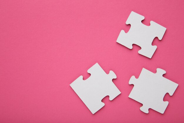 Three white puzzle pieces on pink background