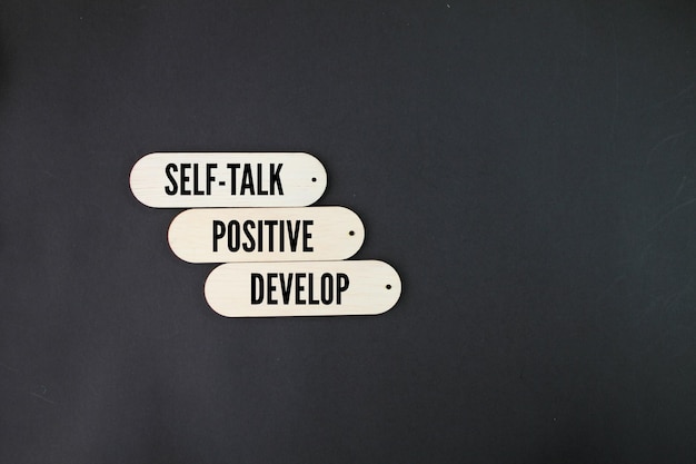 Three white signs with the words self - talk positive develop on them.