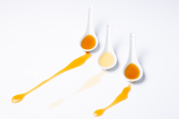 Three white spoons with spilled honey