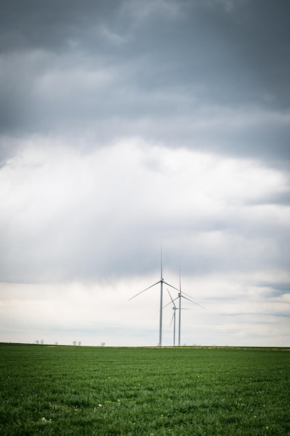 Три ветряные турбины ветряной электростанции производят возобновляемую энергию вертикальное изображение Чистая зеленая альтернативная энергия Энергия ветра для борьбы с изменением климата и глобальным потеплениемНет ископаемого топлива или выбросовЗемля