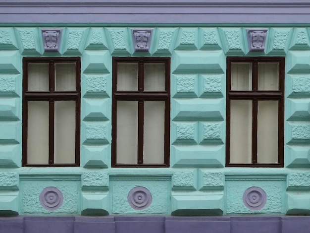 Three windows on the wall with ornaments below and above