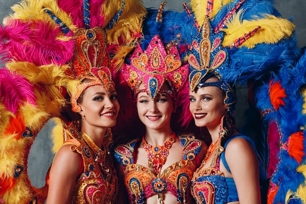 Tre donne in costume di carnevale samba brasiliana con piumaggio di piume colorate.