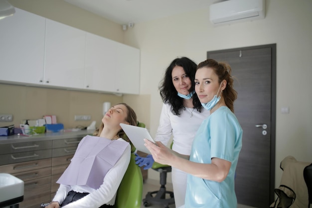 three women in a dental office with a nurse in the background